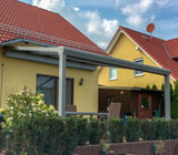 Ein Bild von einem Wintergarten, angebaut an ein Einfamilienhaus mit großzügigem Garten.